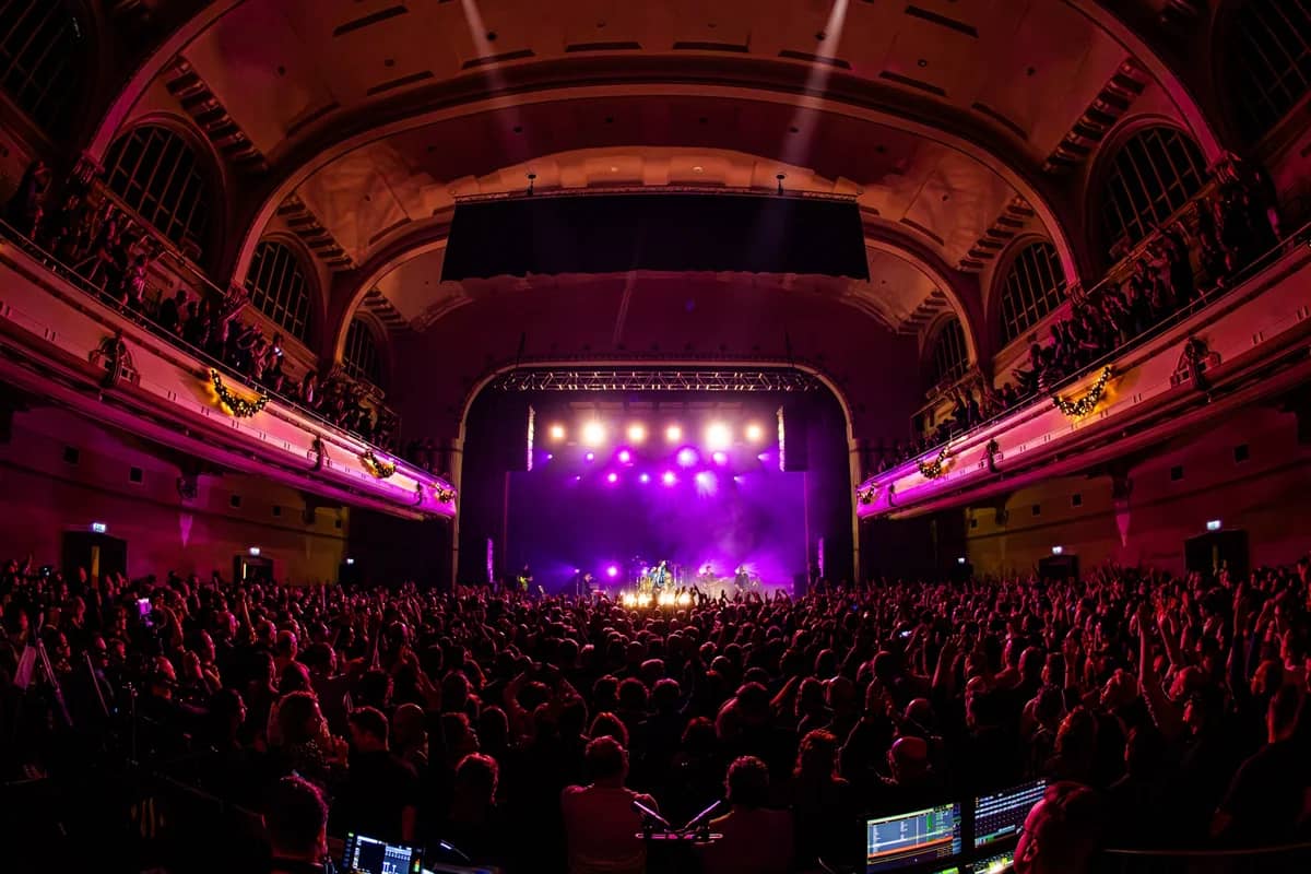 Volle theaterzaal met The Dutch Queen op het podium, paars en roze podiumlicht, uitzicht vanaf de geluidstafel